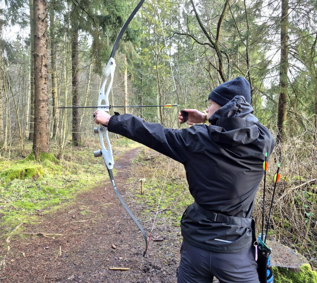 Blankbogenschütze im 3D-Parcours im Wald, Pfeil im 3D-Ziel