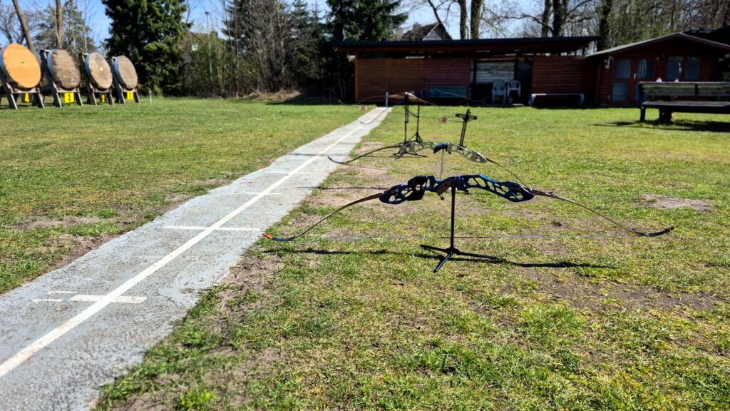 Bogen auf einem Ständer an der Schießlinie, im Hintergrund Scheiben und Vereinsplatz.